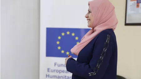 Turkiye_Lady in pink hijab smiling next to EU and CARE banners