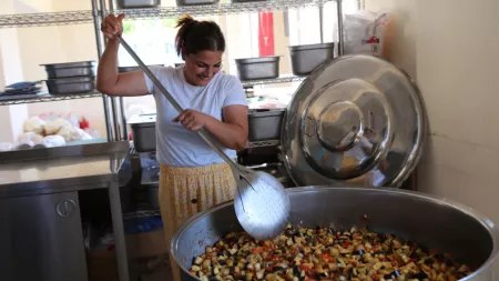 Turkiye_Lady in yellow skirt stirring huge pot of vegetables with huge spoon
