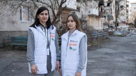 Ukraine_Two ladies in white vests standing in front of destroyed buildings
