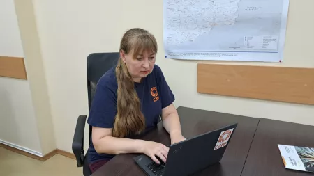 Ukraine_Woman sitting at brown desk wearing CARE shirt working