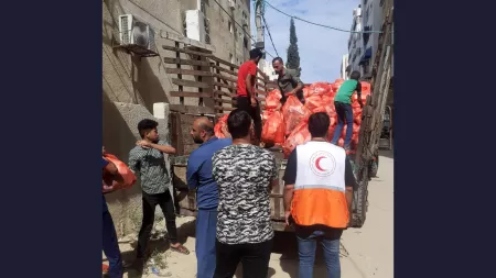 Back shot of men picking up red bags out of a truck