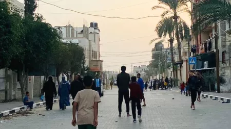 Boy in the forefront and more people from behind walking in a street during sunset