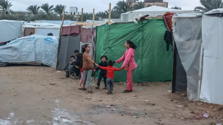 Children in a circle in front of a green tent