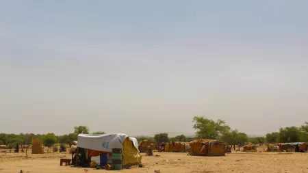 Straw huts spread in dirt field