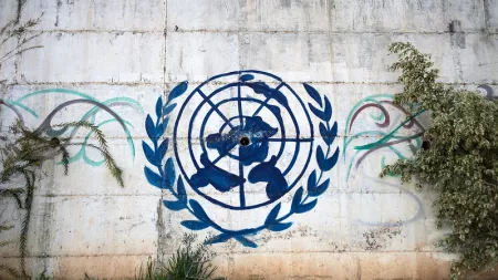 United Nations blue logo on white wall with green lawn in front