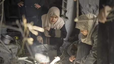 Women cooking on fire amid rubble