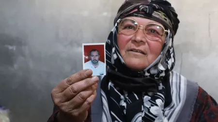 Woman  with glassed and a headscarf showing a photo of a man