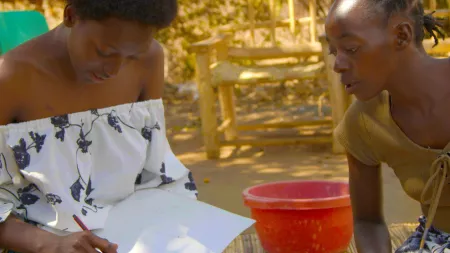 Two women sitting on the floor making notes