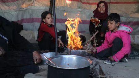 A displaced mother and her children light a fire in their tent to keep warm in northwest Syria.