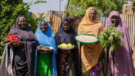Group photo of women showcasing vegetables harvested from their home garden