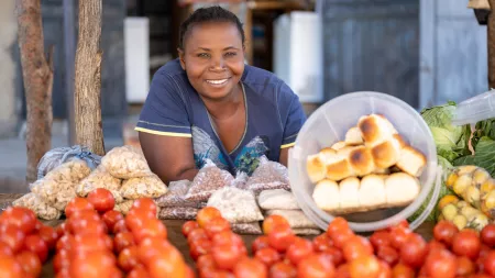 Lady from Zambia smiling in front of her food stall.