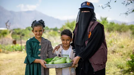 A woman and her children with vegetables that they harvested from their garden