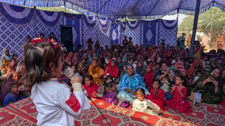 A girl takes center stage at a community event, raising her voice against violence experienced by women and girls. 