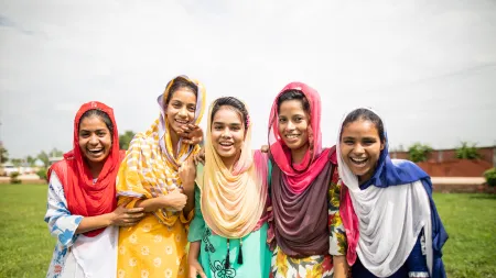 Group of girls wearing colorful clothes and scarves smiling at the camera.