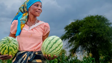 Mary, a farmer, holding watermelons that she grew in her farm.