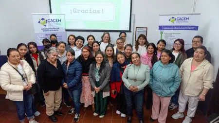 Group of women posing for photo in front of a digital panel and banners.