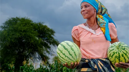 Mary, a farmer, holding watermelons that she grew in her farm.