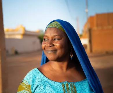Smiling woman with blue headscarf with head turned to the right side