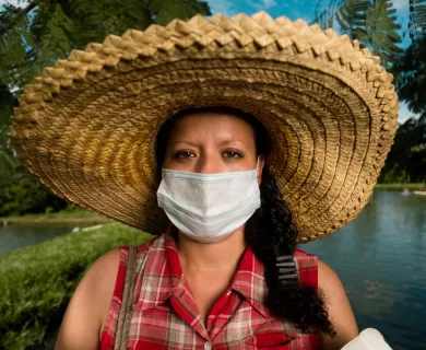 Honduras_Woman with big hat and mask standing by water body