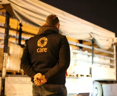 Man wearing CARE's jacket in front of truck