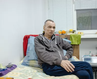 Ukraine_Sickly man sitting on bed next to oxygen machine