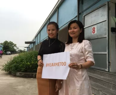 Vietnam_Two women holding a sign smiling outside factory door