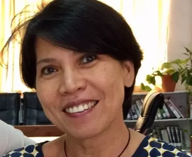 Headshot of woman with short straight black hair, smiling, wearing a black necklace
