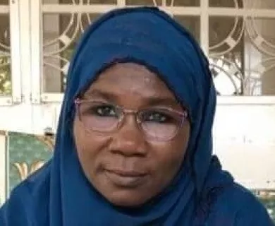 Headshot of woman looking serious to the camera wearing glasses and a headscarf