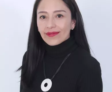 Headshot of woman with half smile, long black straight hair. Wearing a black turtleneck shirt