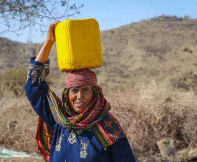 Yemen_Lady with colourful scarf and water bucket on her head