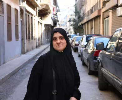 Woman wearing black scarf standing in a narrow street