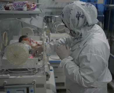 Syria_Dr with hijab on handling newborn in incubator