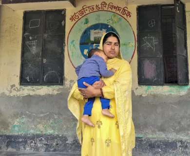 Bangladesh_Woman with yellow sari standing in front of maternal health cinic with son