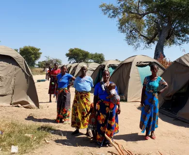 Zambia_Women standing in formation in between displacement camp tents