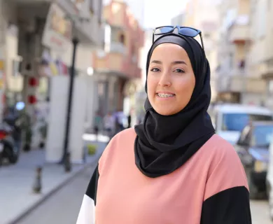 Turkiye_Hijabi in pink black and white sweater smiling in the middle of the street