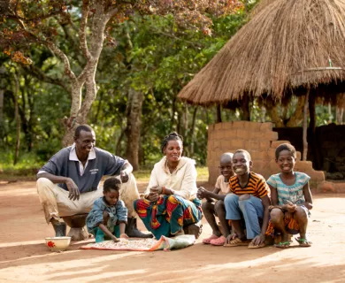 Zambia_Family sitting on the floor with tin bowls laughing