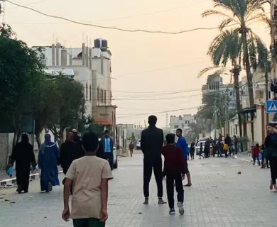 Boy in the forefront and more people from behind walking in a street during sunset