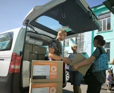 Volunteers from CARE distribute boxes of essential supplies from the back of a van to local residents in Pokrovsk, Ukraine, amid ongoing humanitarian efforts.