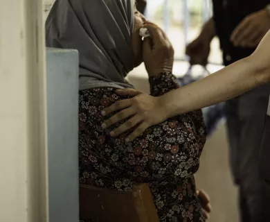 Backshot of a woman drying her face with a tissue with a person's hand on her shoulder
