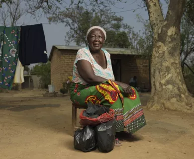 Woman sitting on chair, wearing green and yellow shirt and flower-pattern shirt