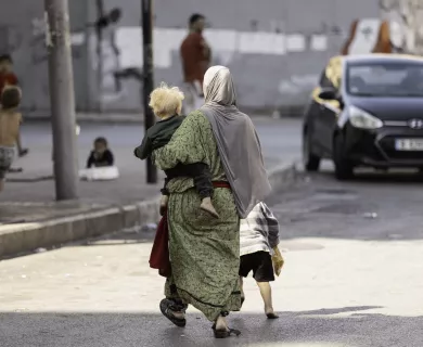 Back shot of woman carrying a baby while walking on the street