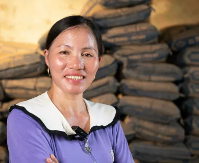 Portrait of woman with arms crossed with produce bags piled up in the background