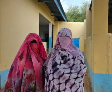 Two women with patterned clothes wearing head scarves and face covers